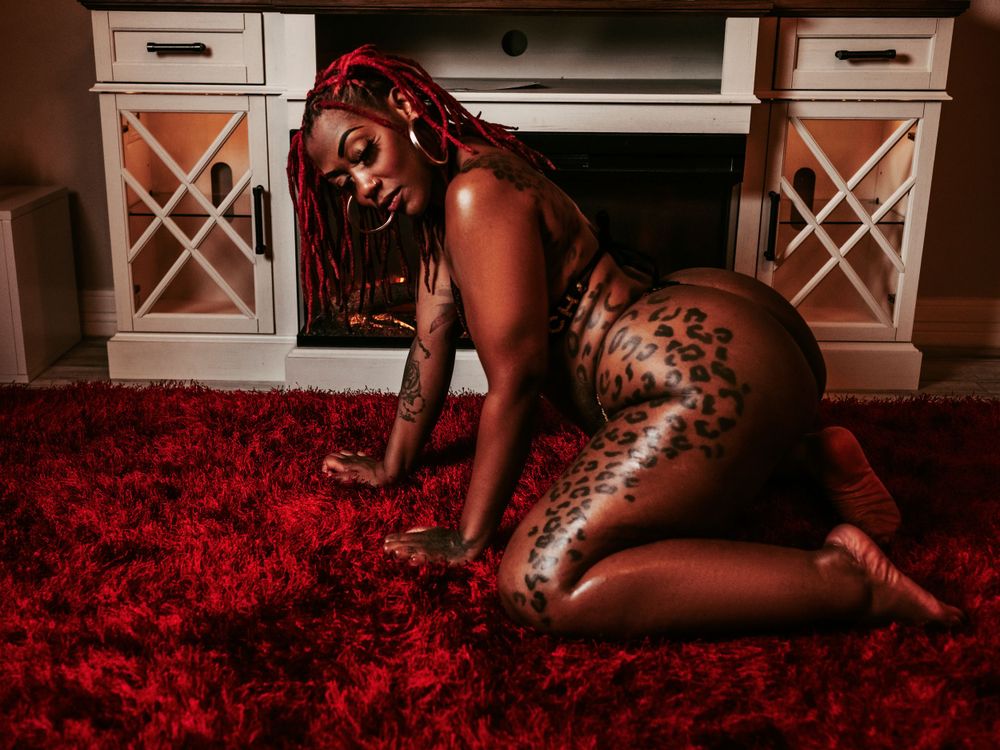 Boudoir photo of a woman on a red rug by the fireplace, exuding warmth and elegance.