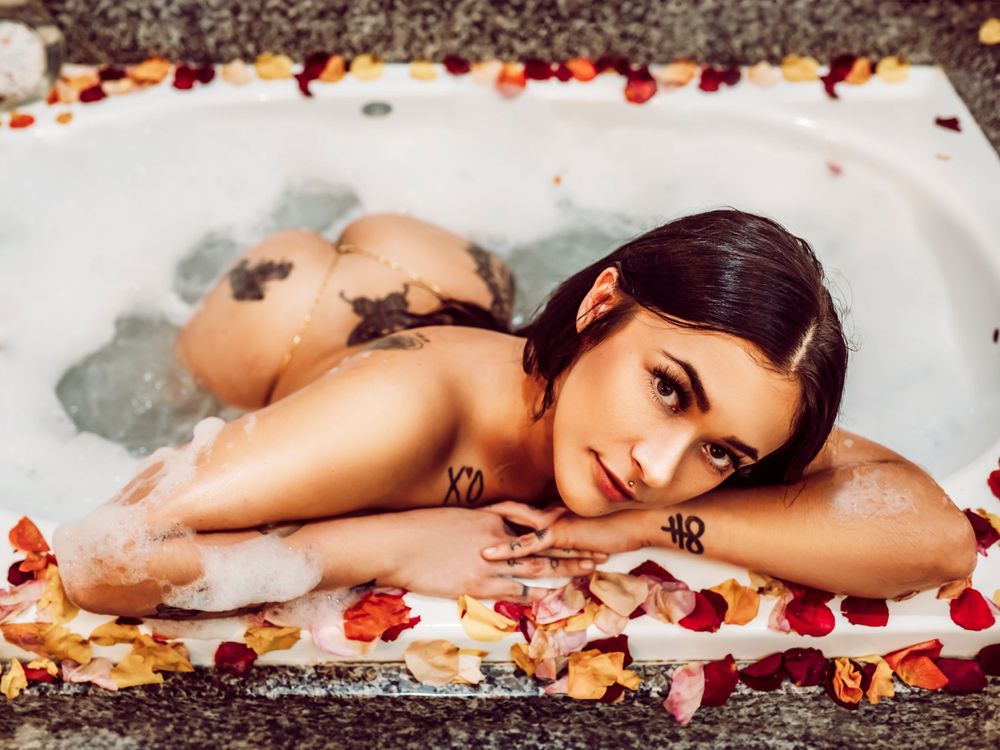 Woman in a bathtub covered in rose petals, creating a steamy and elegant moment of relaxation.