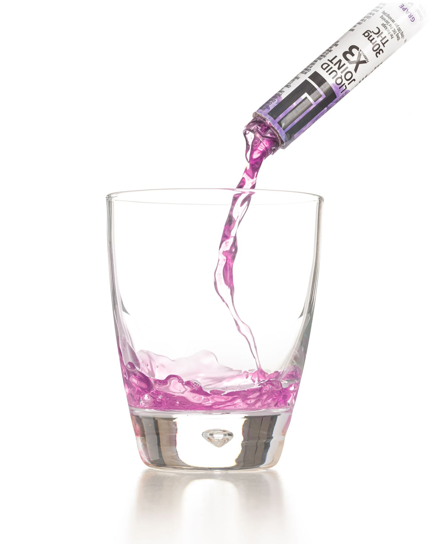 Pink liquid being poured from a tube into a clear glass against a white background.
