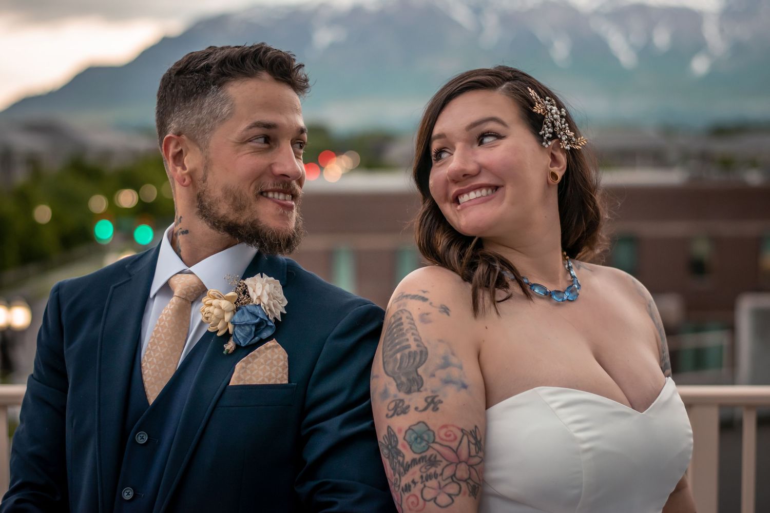 Couple shares an intimate moment outdoors with soft lighting as the bride's white dress and groom's dark suit complement each other.