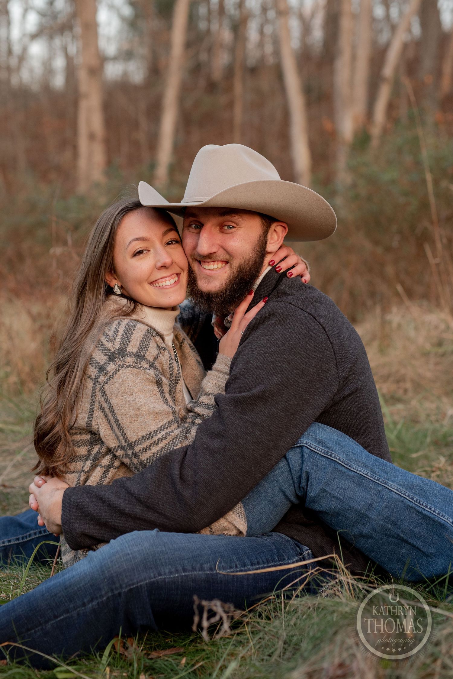 A couple in casual western wear shares a loving moment in an autumn field.
