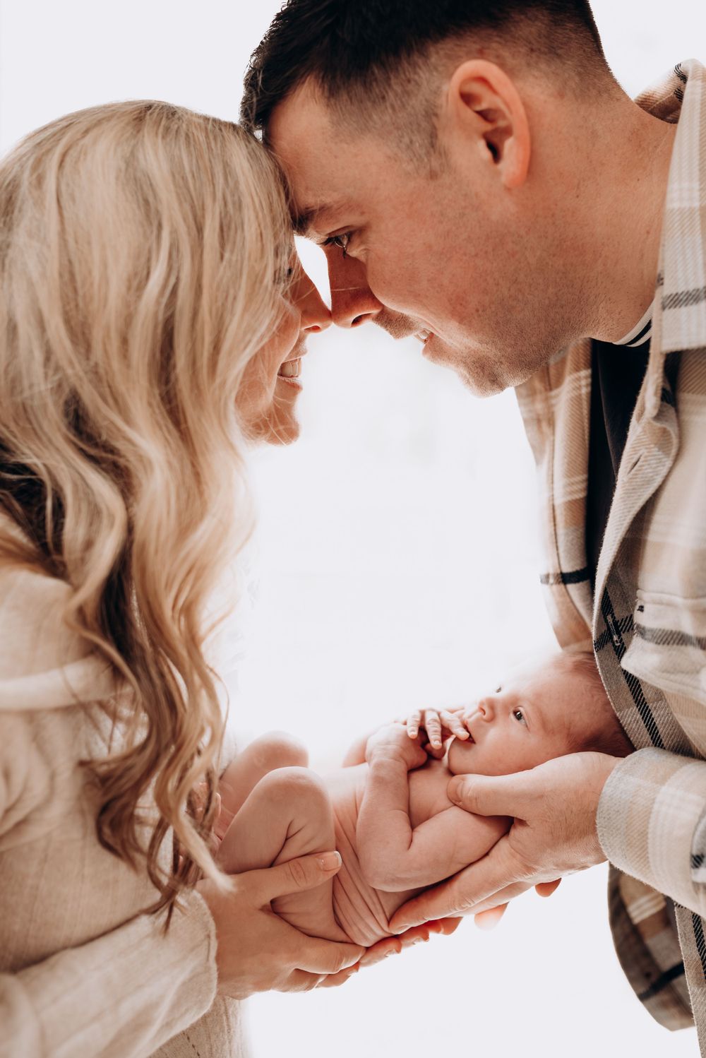 Tender newborn photography session showing intimate family moments on white background.