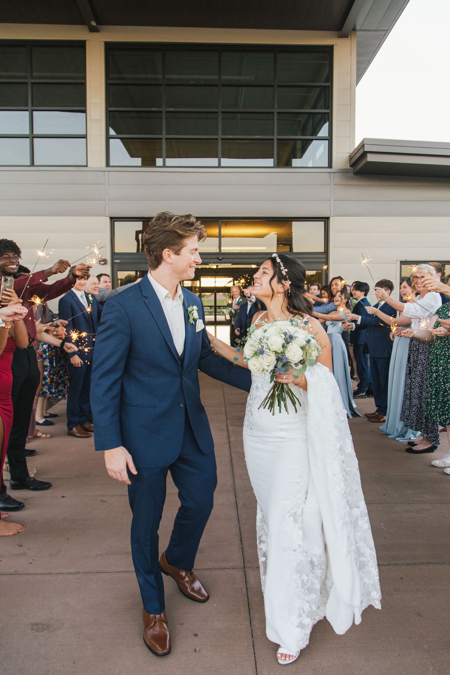 Wedding exit celebration with guests cheering outside a modern building.
