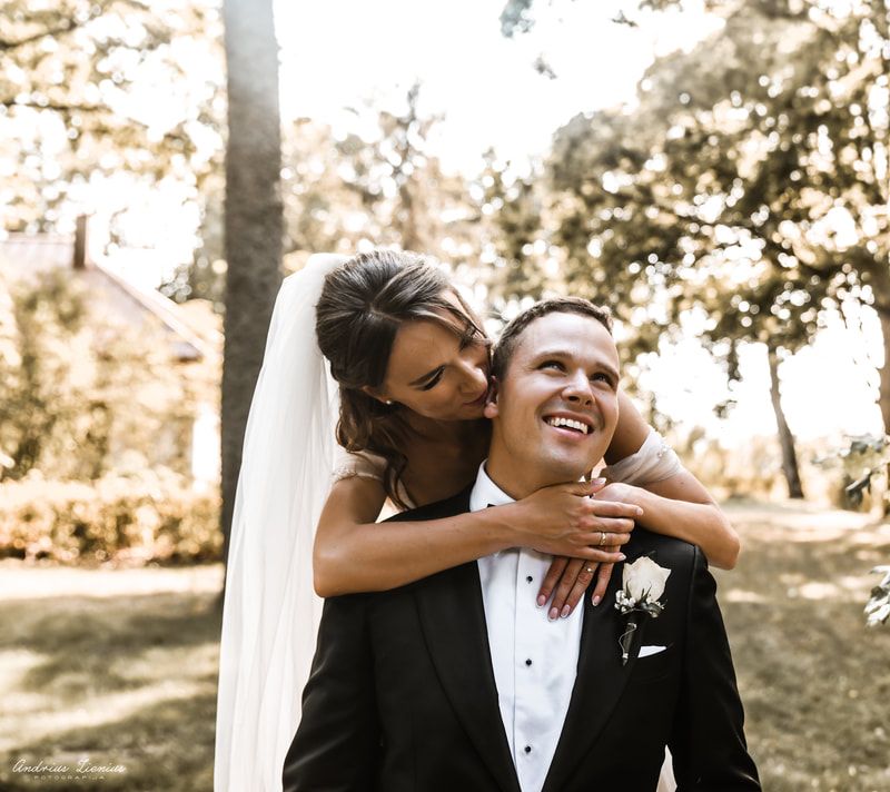 A joyful wedding couple embracing outdoors in a sunlit forest setting.