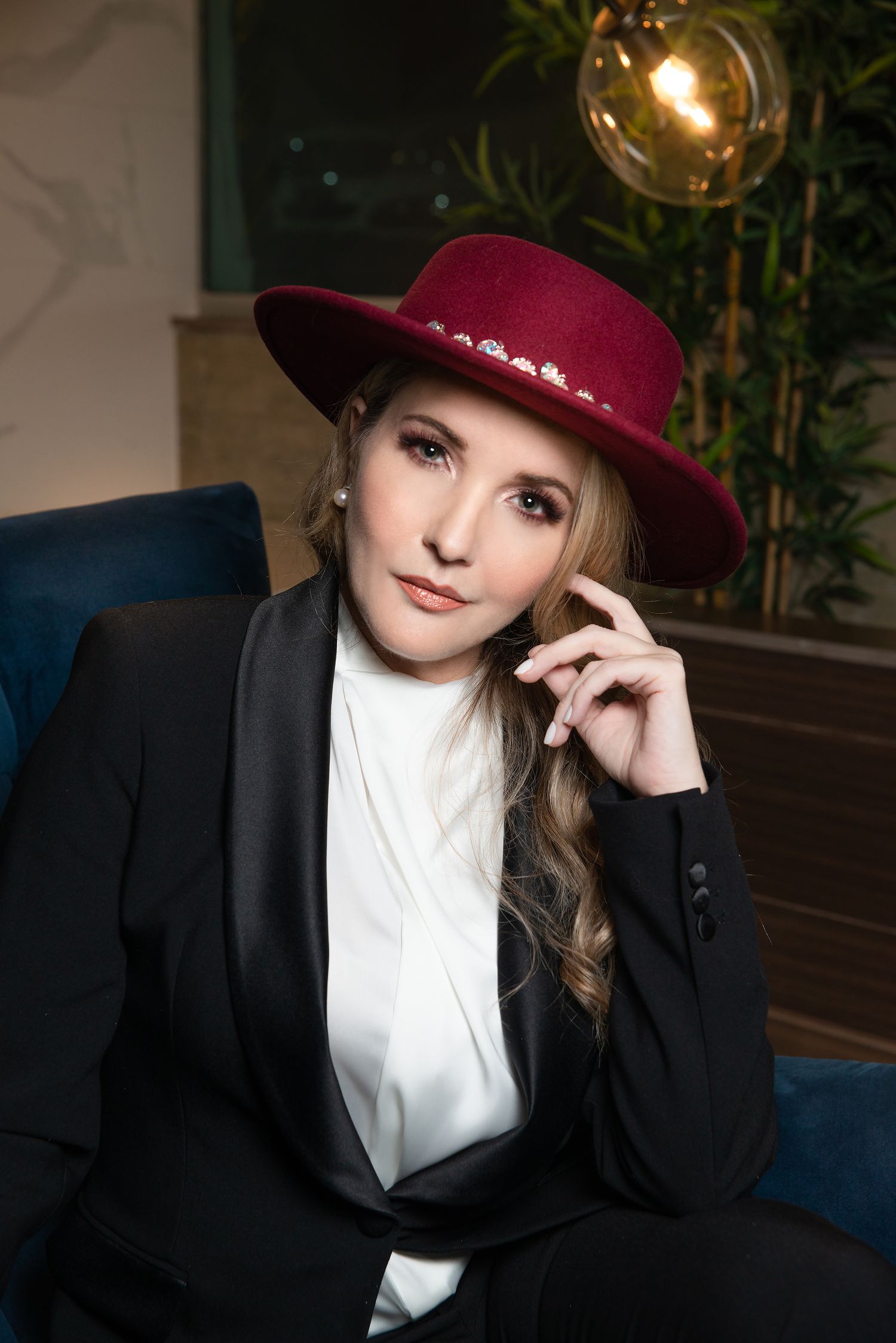 Stylish portrait featuring burgundy hat and black blazer in modern setting.