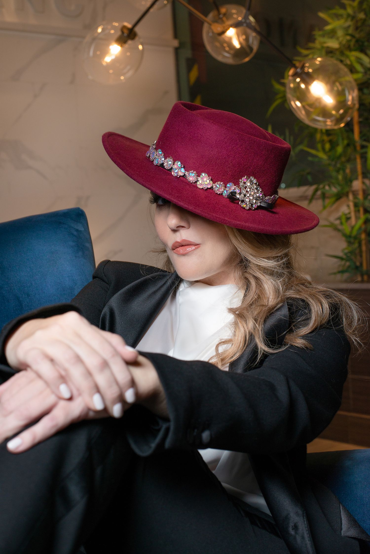 Close-up shot highlighting burgundy hat with crystal embellishments against modern decor.