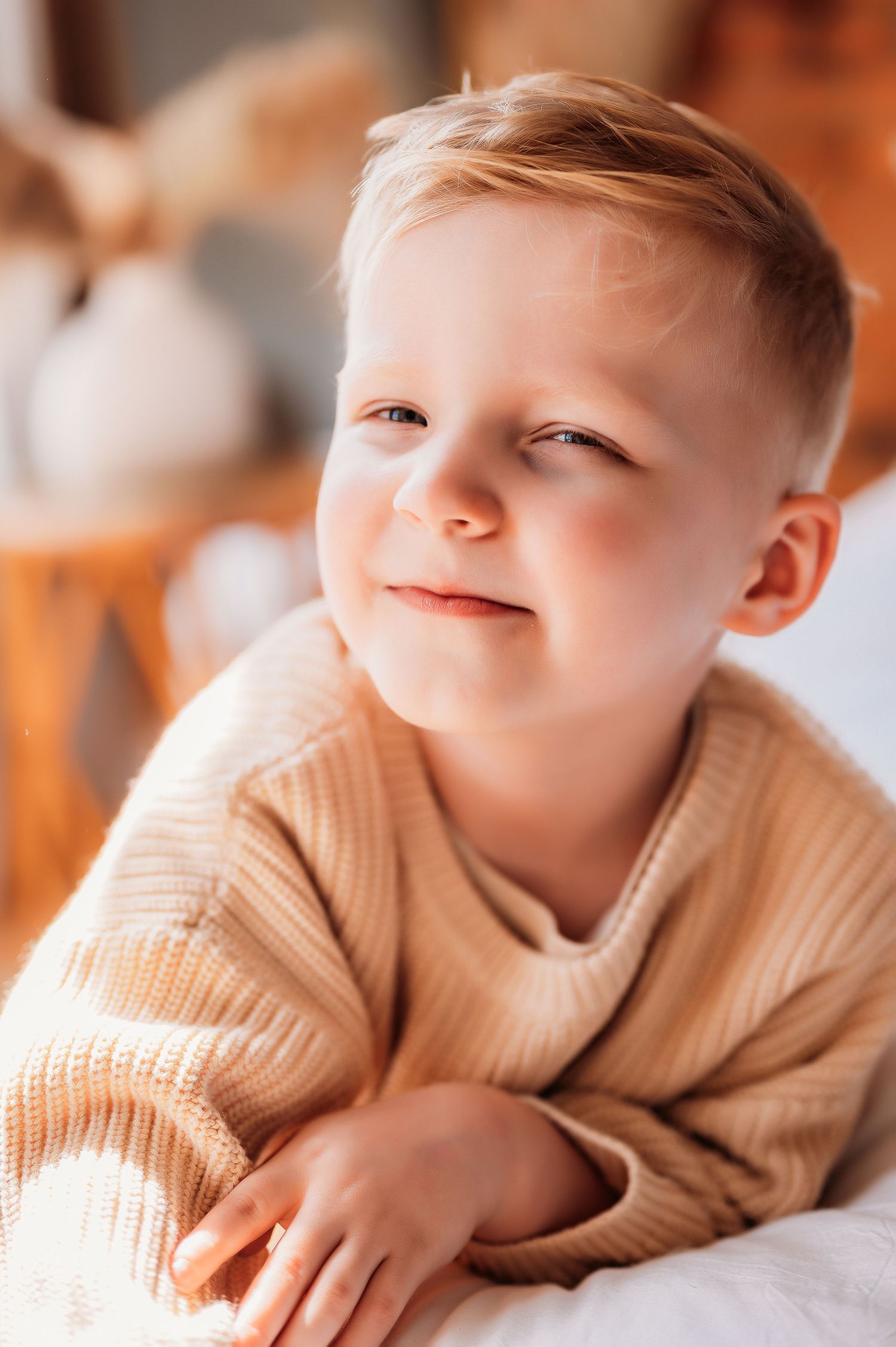 Young boy wearing chunky sweater grinning in home in Staten Island, NY