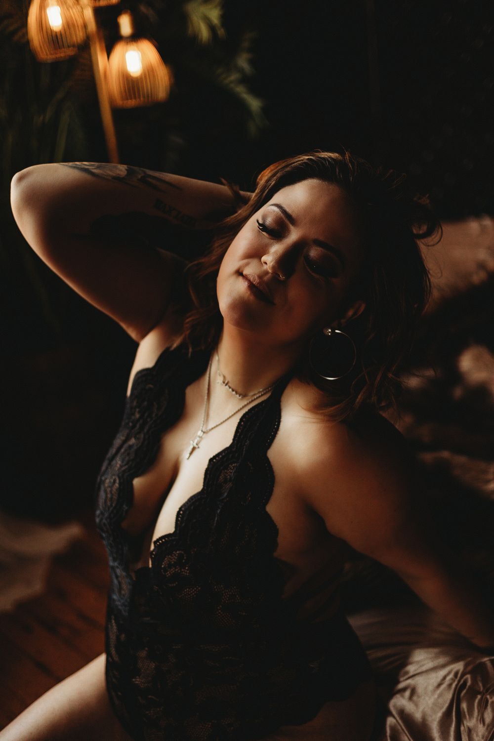 Artistic boudoir photo with pendant lights and black lace detail.