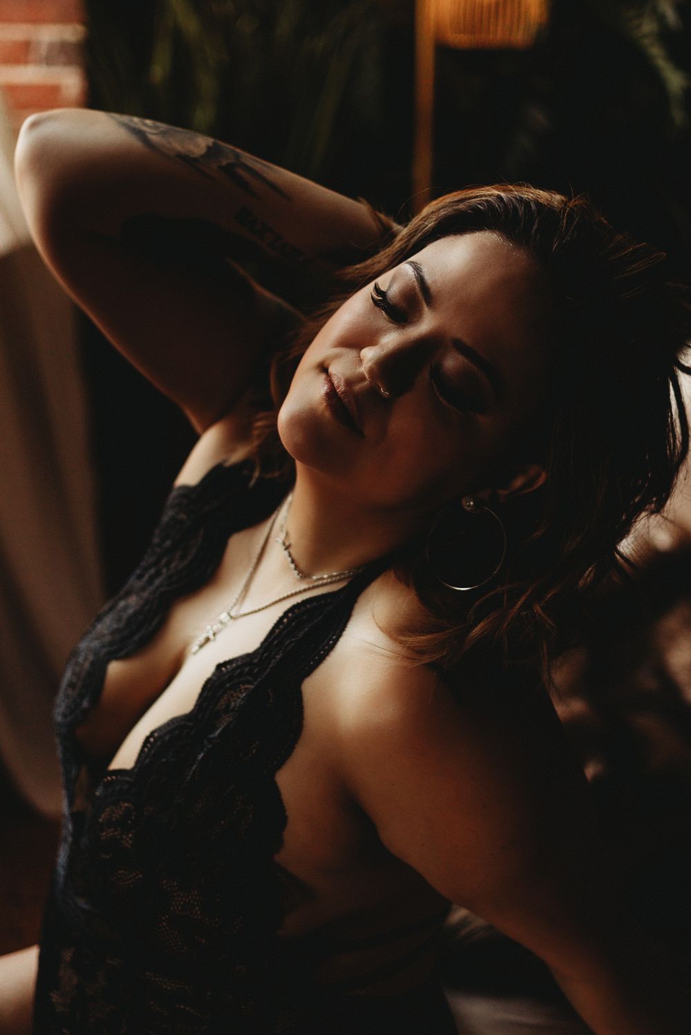 Moody portrait in black lace lingerie with warm lighting.