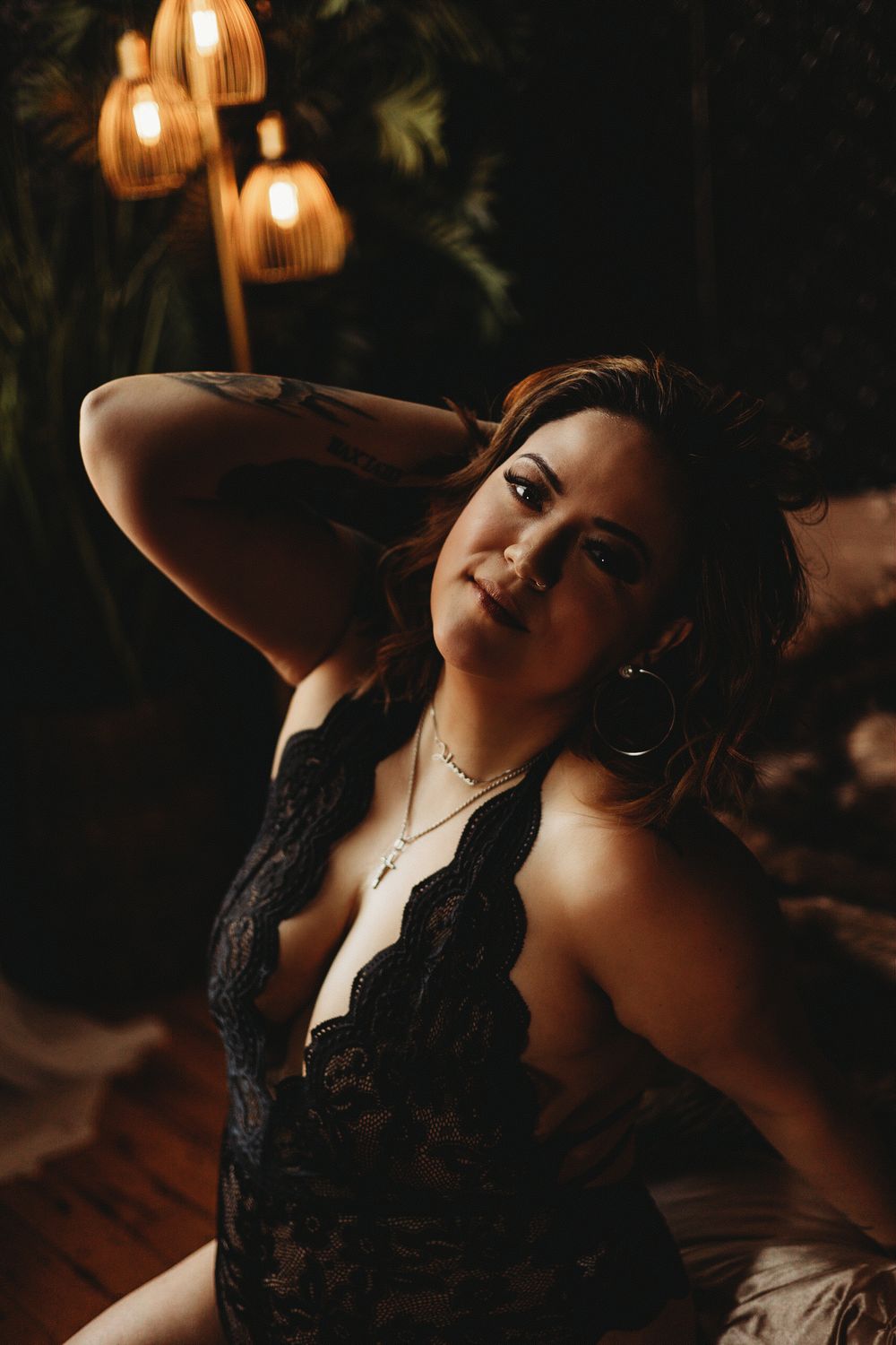Portrait against dark background with pendant lighting and lace neckline.