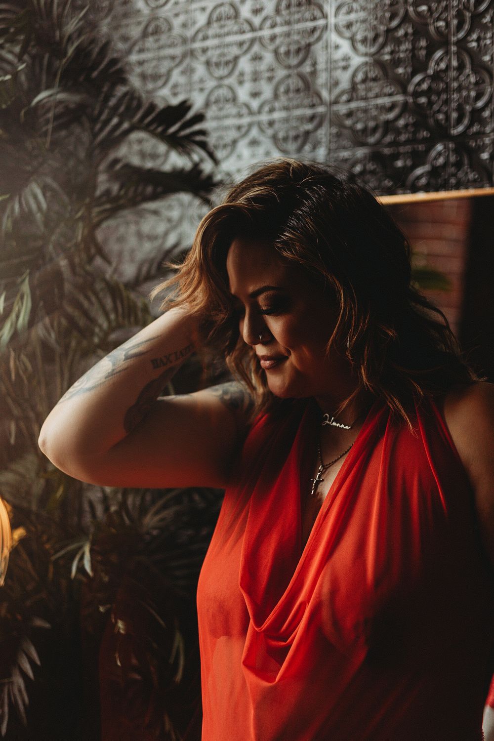 Dramatic portrait in red draped fabric against patterned wall.