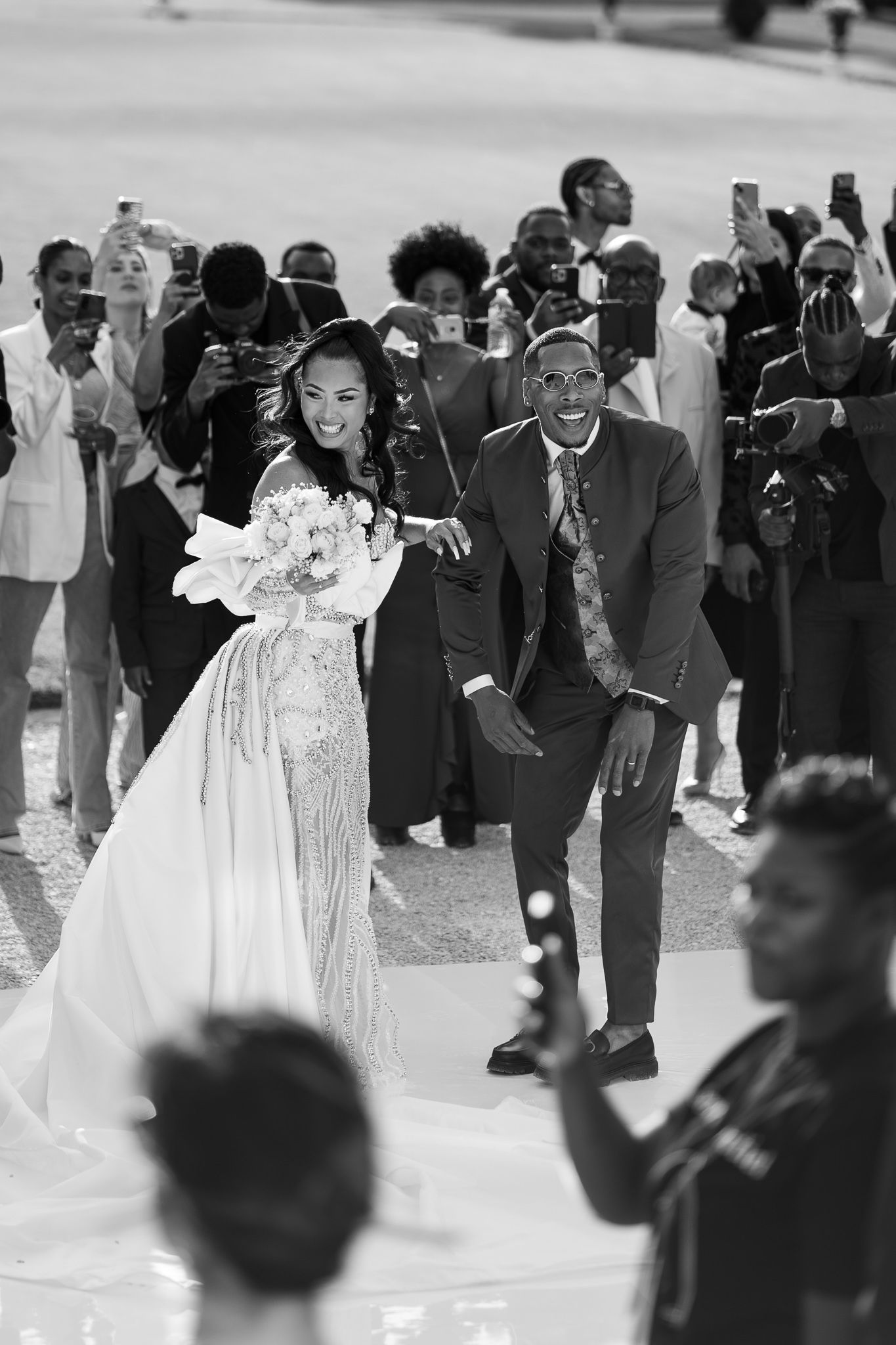 A black and white photo sequence showing a couple dancing at a wedding celebration surrounded by guests.