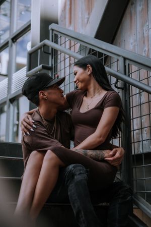 Couple in brown clothing share romantic moments on industrial stairs.