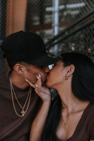 A couple in dark clothing share tender kisses in a moody photoshoot sequence.