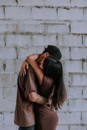 Intimate couple photography against white brick wall background showing tender embraces.