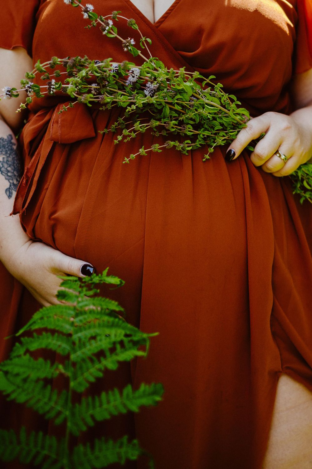 Close-up detail of rust-colored fabric with delicate ferns and greenery.