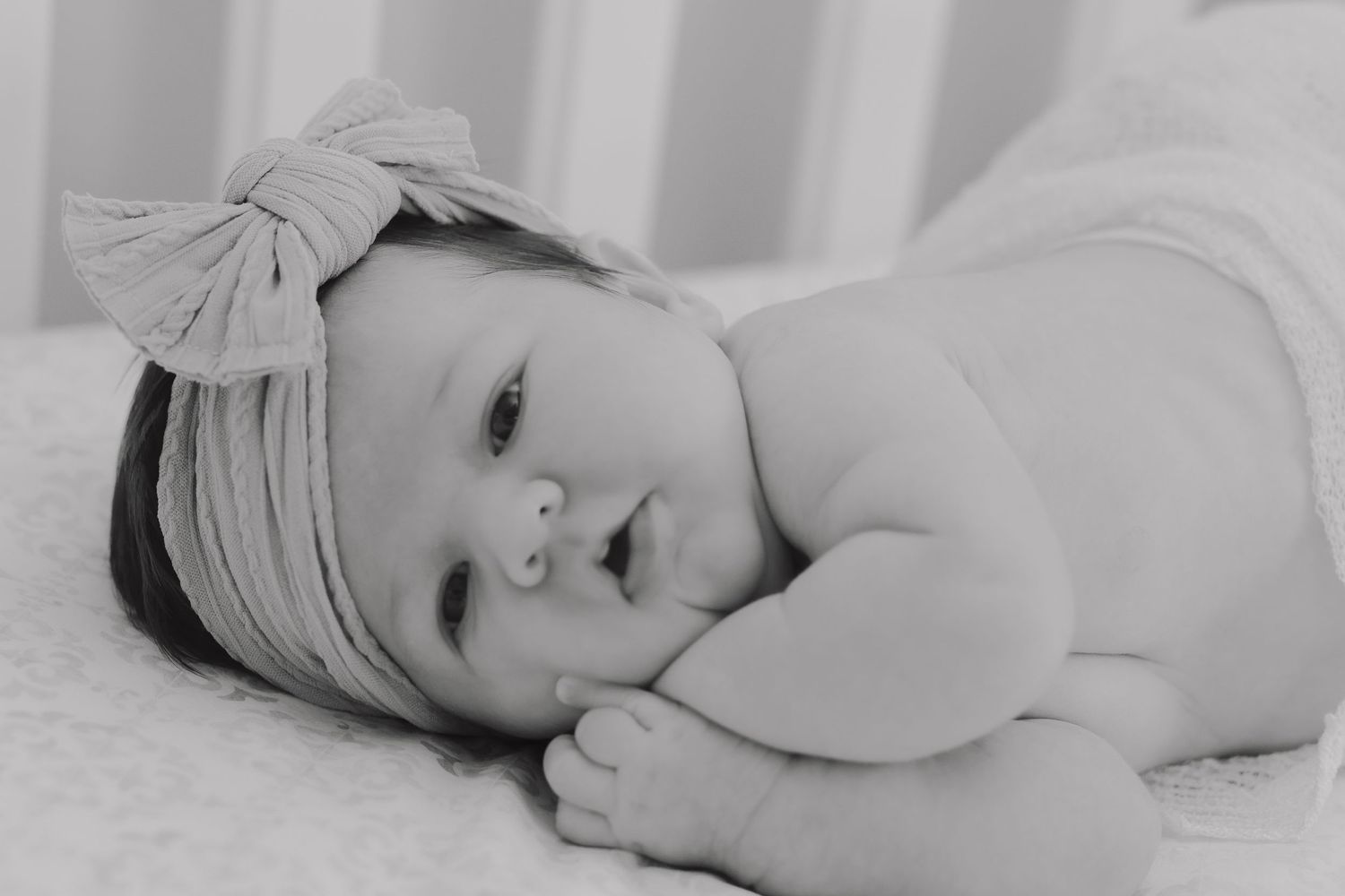 An adorable chubby baby snuggling in her crib for a picture perfect newborn photo