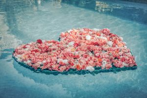 Rose petals are floating in a heart shape in the water during a luxury surprise proposal in Mallorca.