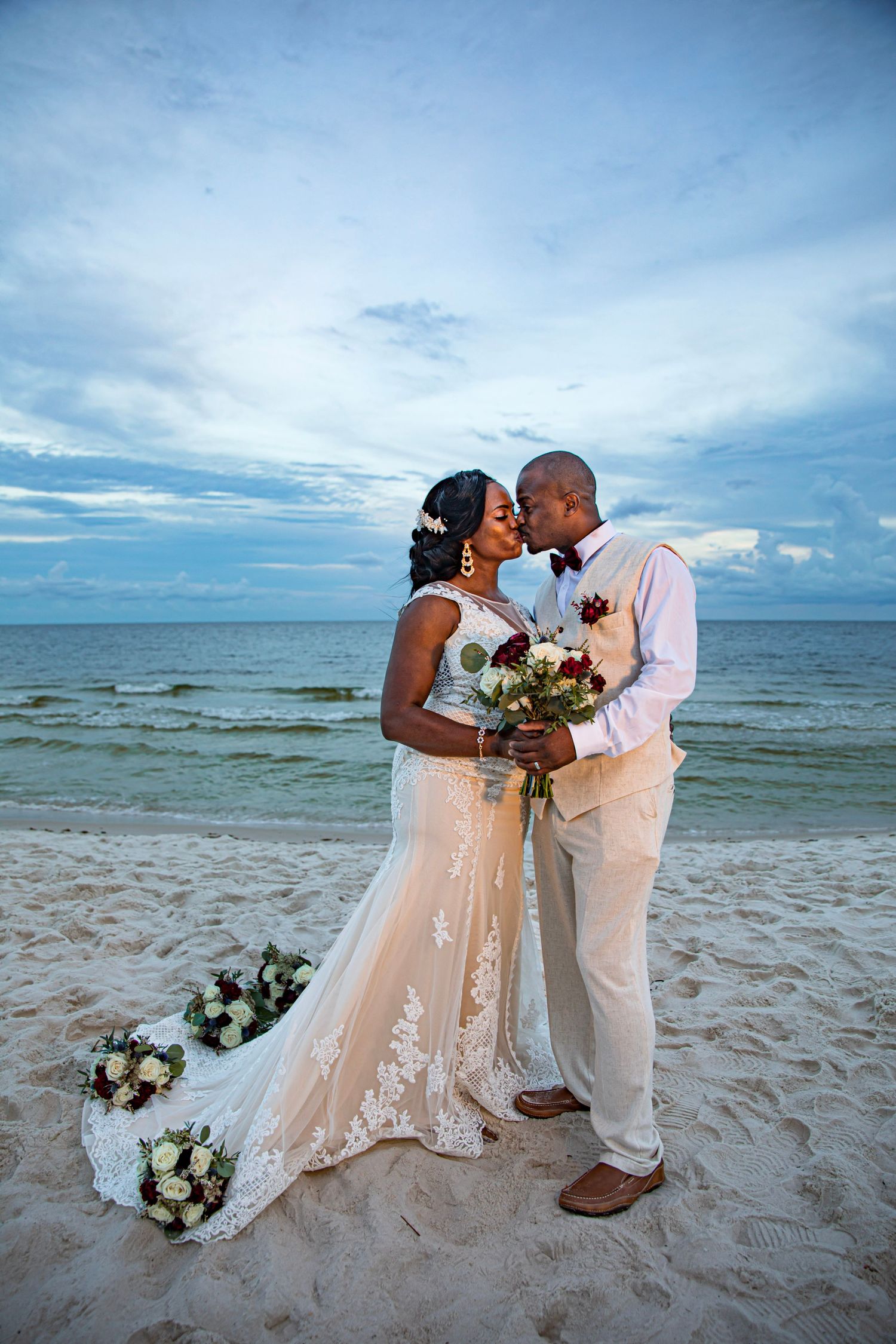 Beach wedding ceremony scene with floral arrangements and crashing waves in the background.