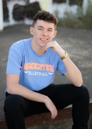 Person in blue Momentum Volleyball shirt poses casually outdoors.