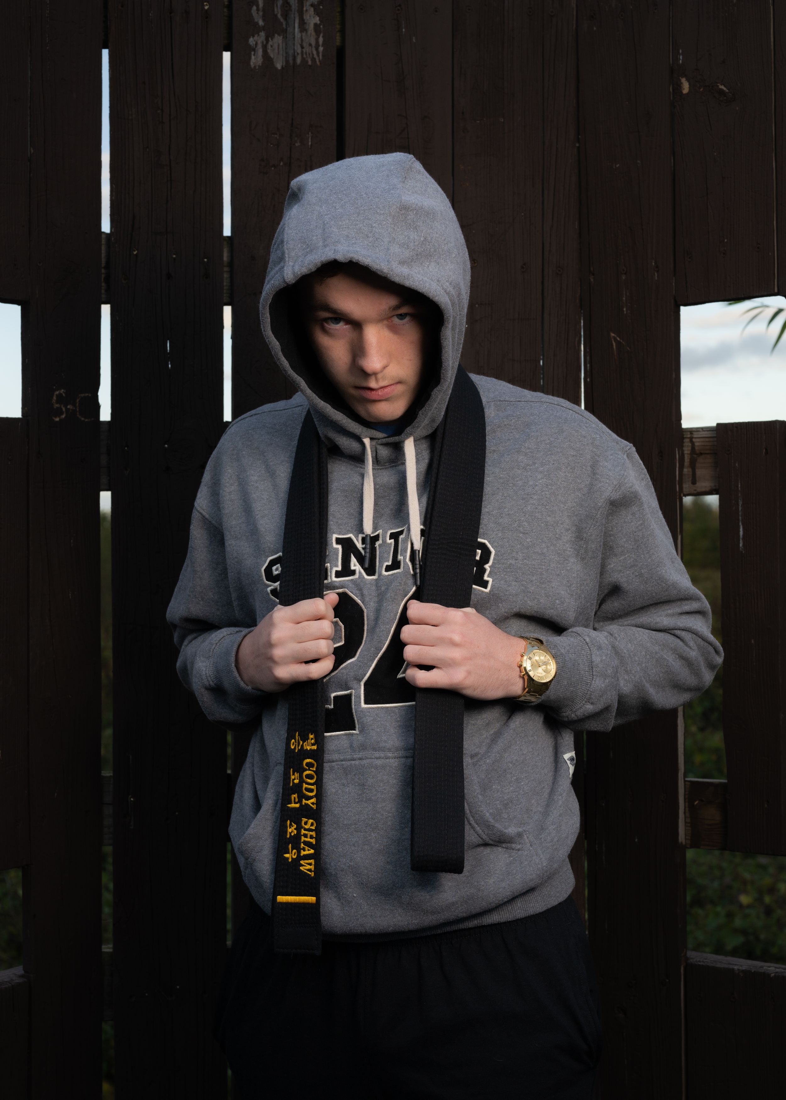 Person in grey Senior hoodie poses against dark wooden background.