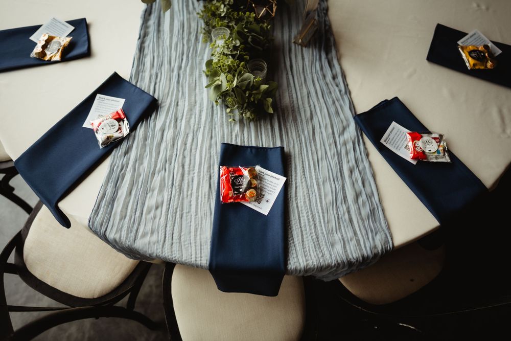 Overhead view of wedding table settings with navy napkins and centerpiece.