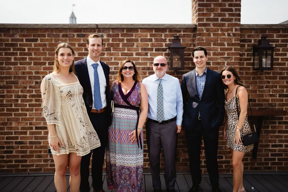 Group poses together against brick wall at formal event.