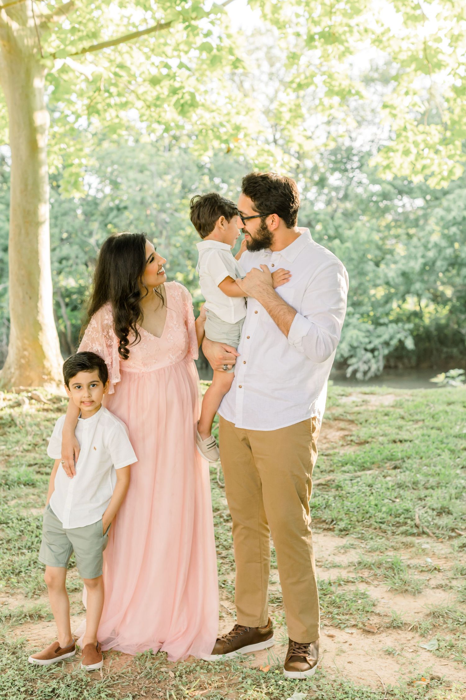 Family of four shares intimate moment together outdoors wearing coordinated pink and white outfits.