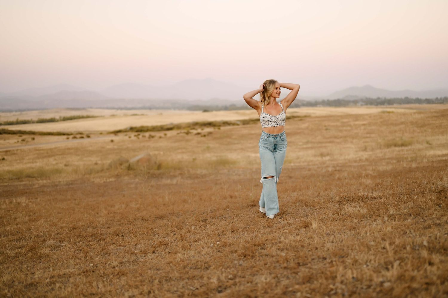 high school senior portrait by Tiffany Kelterer, of Ventura high school senior standing in golden grass during sunset