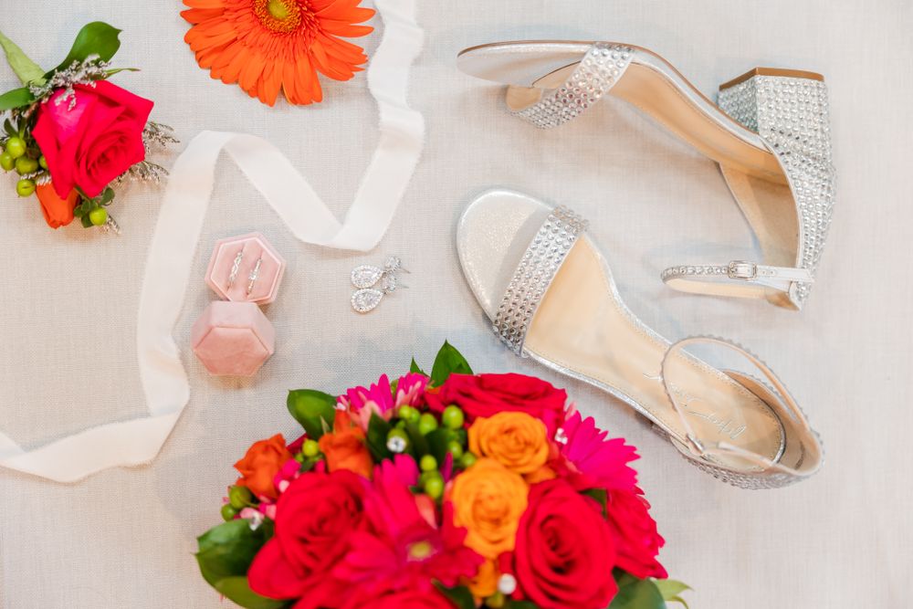 Wedding accessories flatlay with colorful bouquet, sparkly shoes, and jewelry.