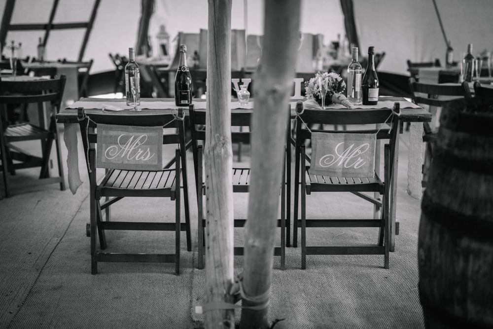 Black and white photo of vintage folding chairs and tables inside a tent venue.