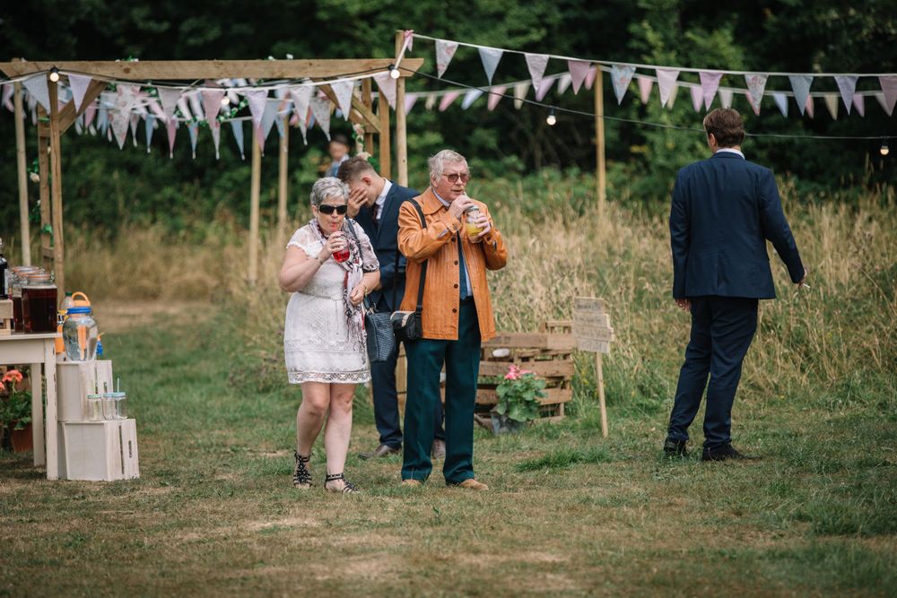 Outdoor event setup with white bunting decorations and wooden crates in a grassy field.