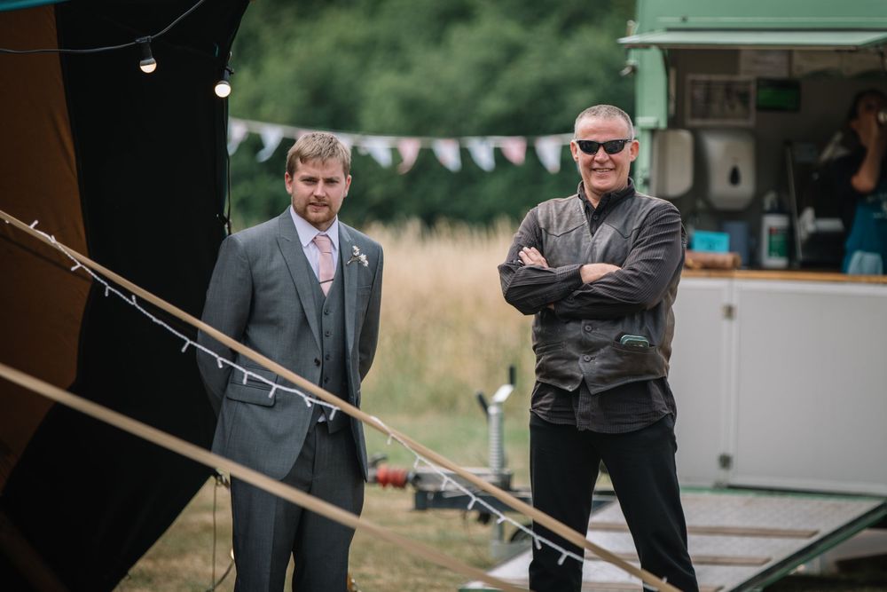 Two men standing near a tent entrance at an outdoor event.