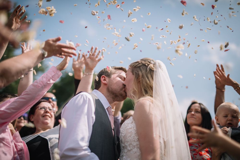 Confetti fills the air during an outdoor wedding celebration.