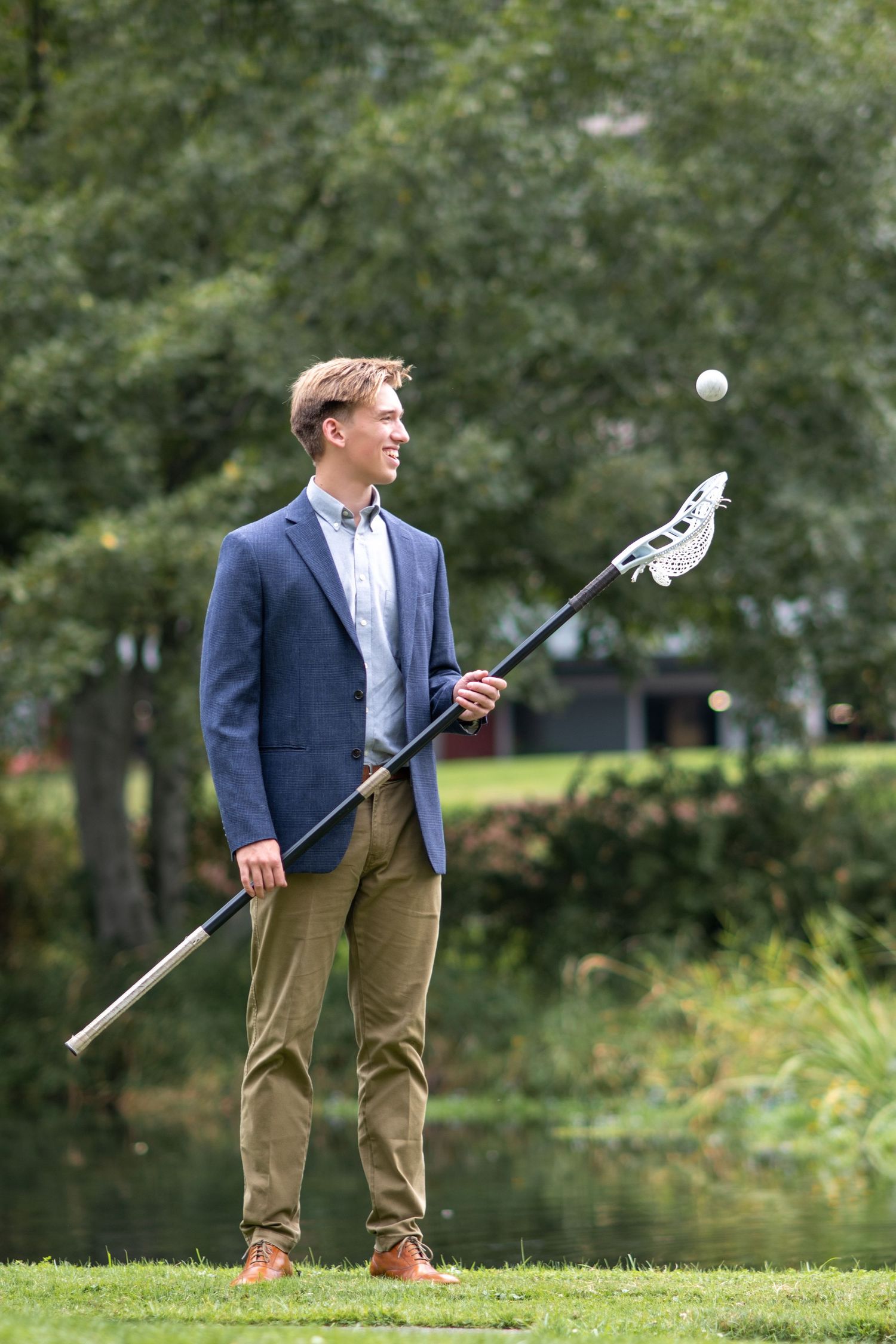 senior from lake ridge high school using lacrosse pole tossing ball in the air. wearing nice suit jacket