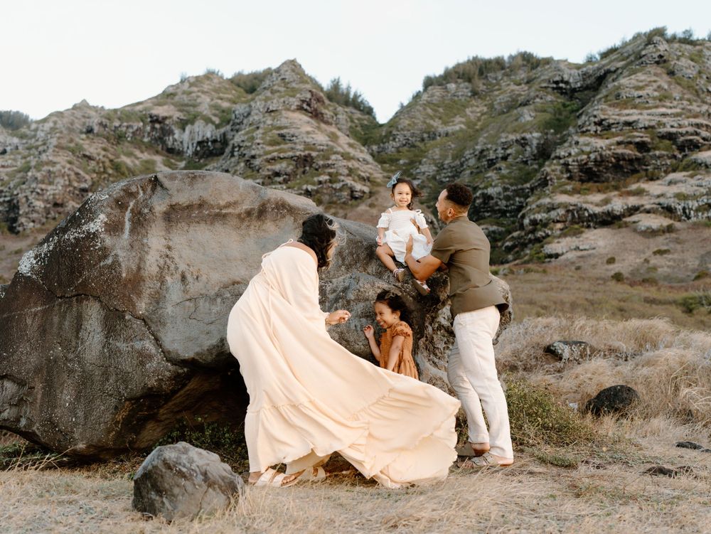 A family photoshoot by Moments With Kell with a rock backdrop on Oahu in Hawaii with parents and children exploring