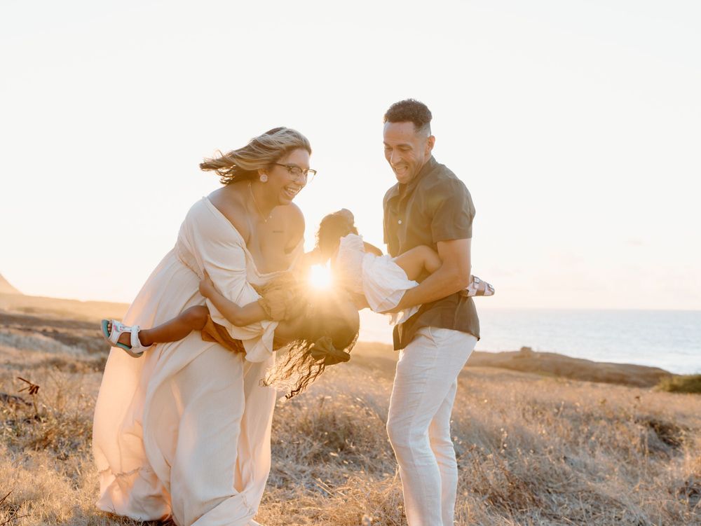 A family photoshoot by Moments With Kell with a sunset backdrop on Oahu in Hawaii with parents and children playing