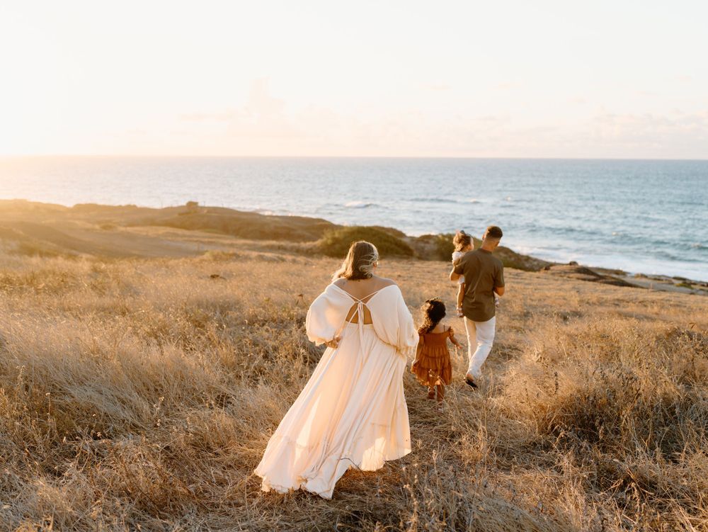 A family photoshoot by Moments With Kell with a ocean backdrop on Oahu in Hawaii with parents and children walking
