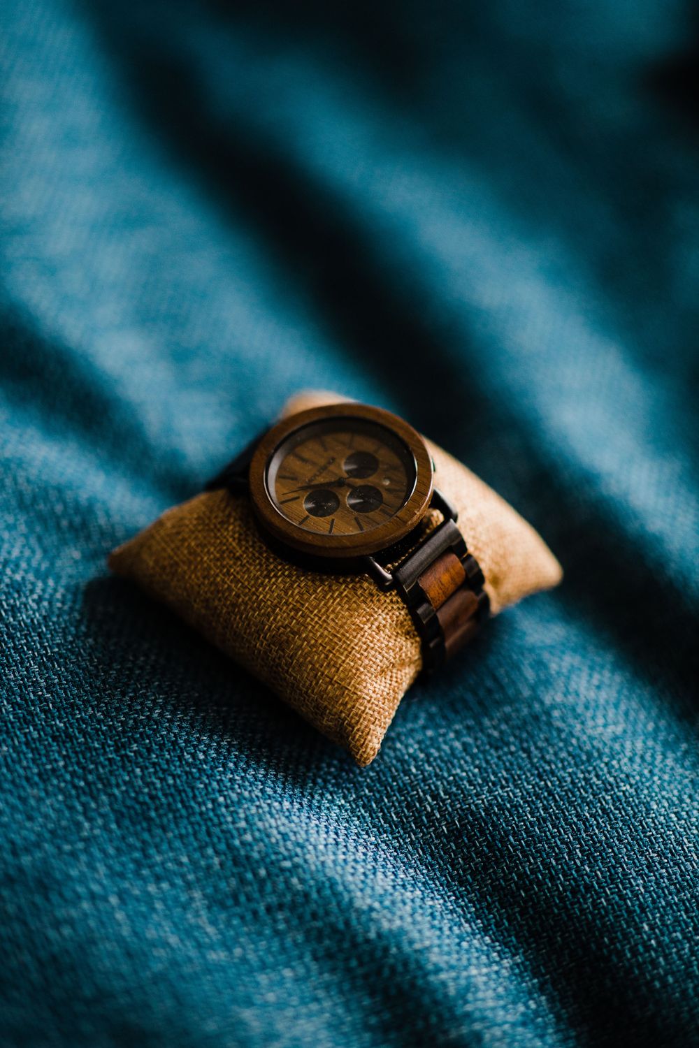 Wooden watch on blue textured fabric with vintage style photography.
