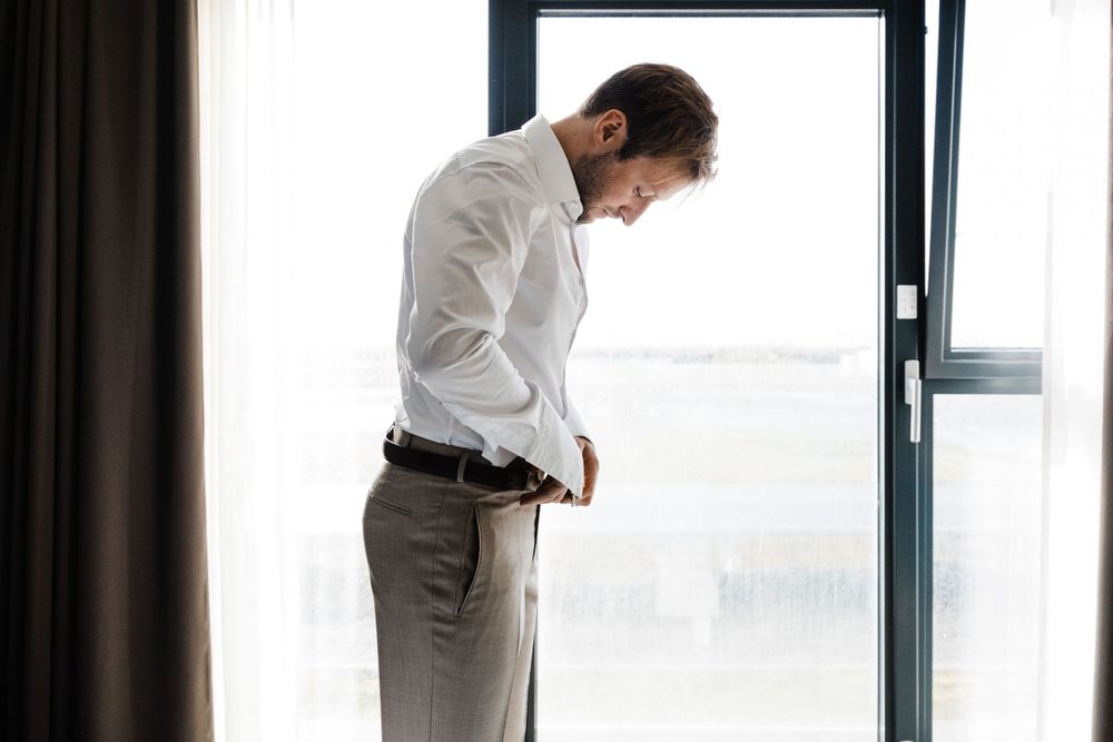 Person in formal attire looking out window in contemplative pose.
