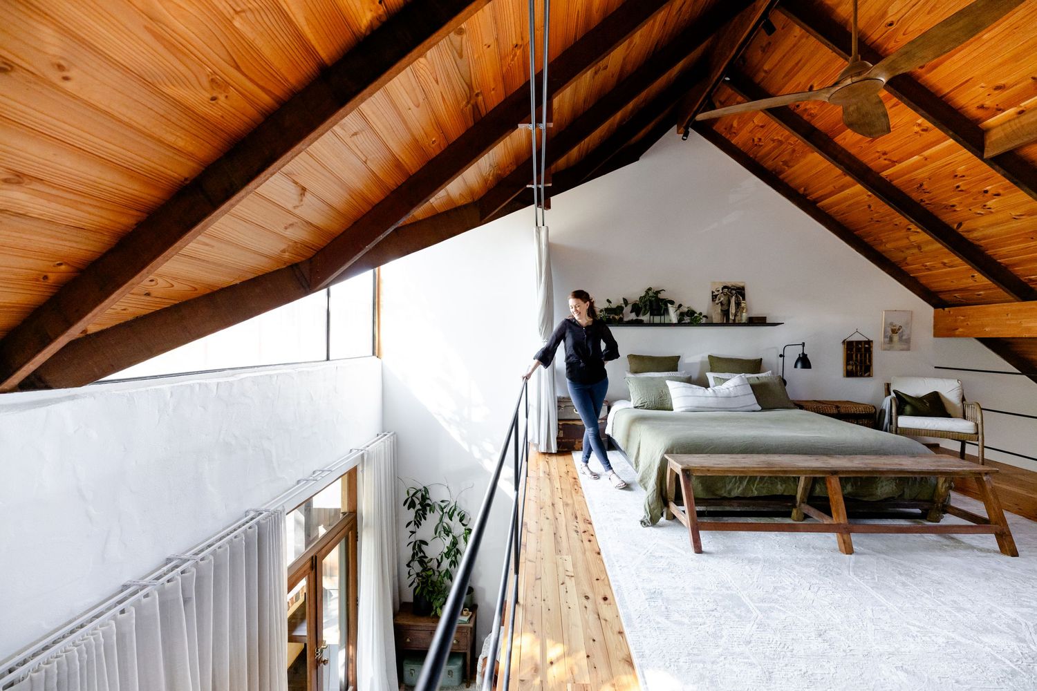 Modern loft bedroom with sloped wooden ceiling and minimalist decor features a cozy sleeping area.