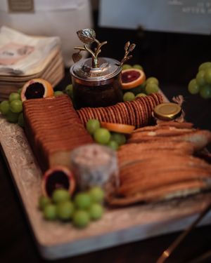An artfully arranged charcuterie board with crackers, grapes, and decorative serving pieces.