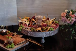 Gourmet appetizers artfully displayed on an elevated stone platter with charcuterie and fresh grapes.