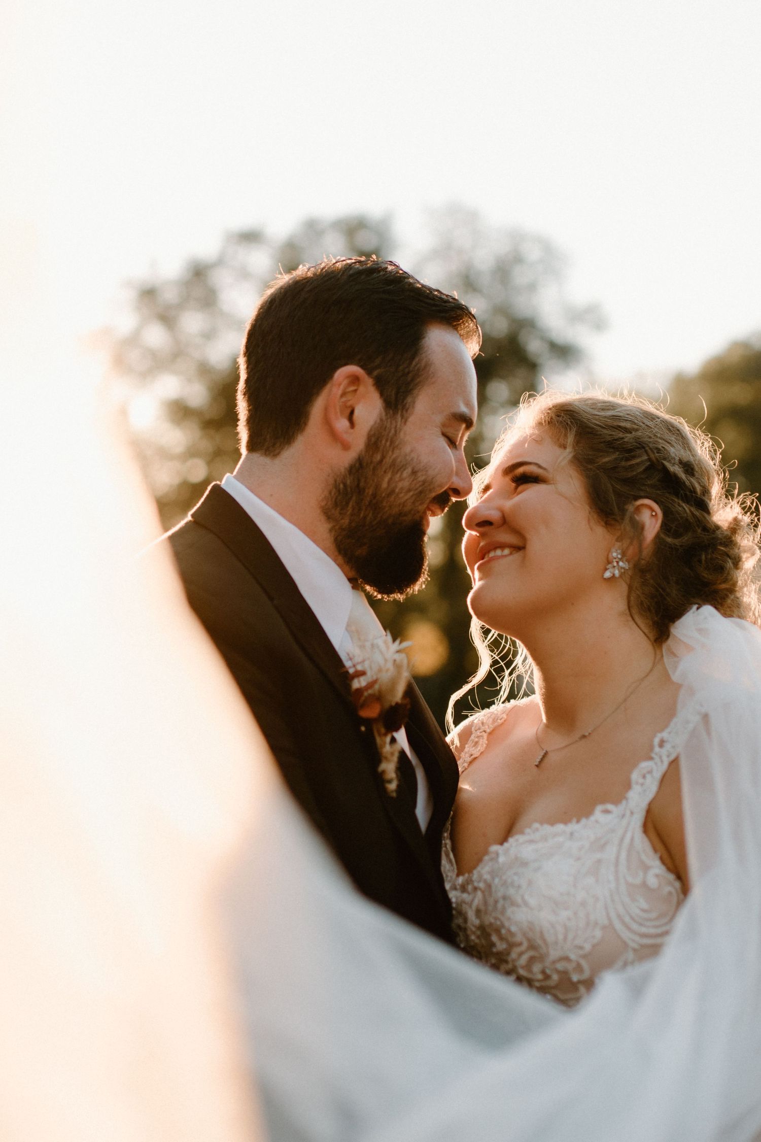 Romantic sunset portrait of newlyweds sharing intimate moment.