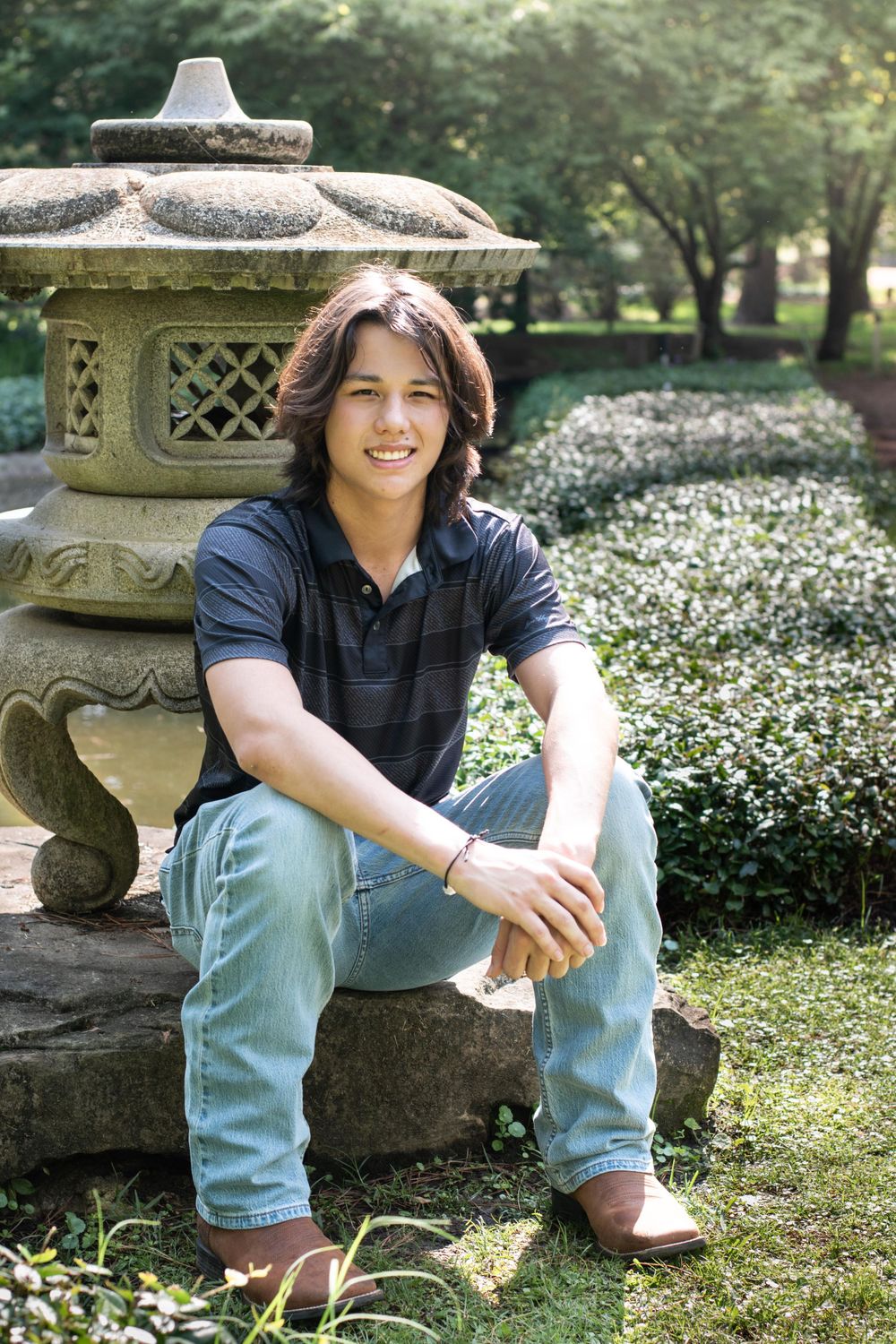 Casual portrait by an ornate stone garden lantern surrounded by white flowers.