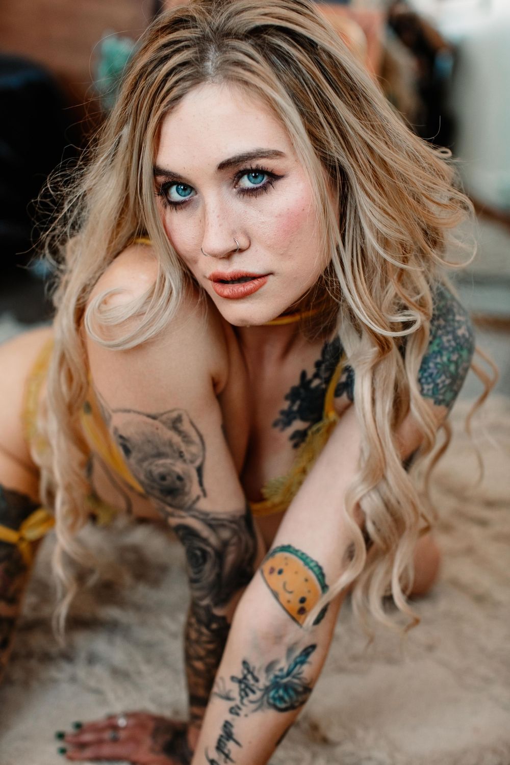 Close-up boudoir portrait highlighting artistic tattoos and natural makeup.