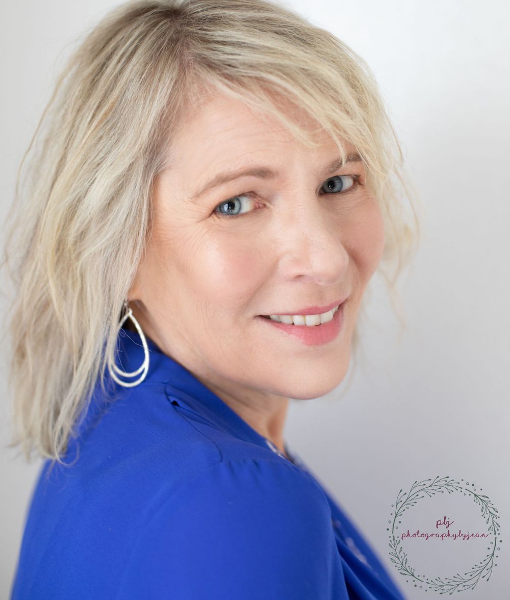 Professional headshot in bright blue top with blonde hair and silver hoop earrings.