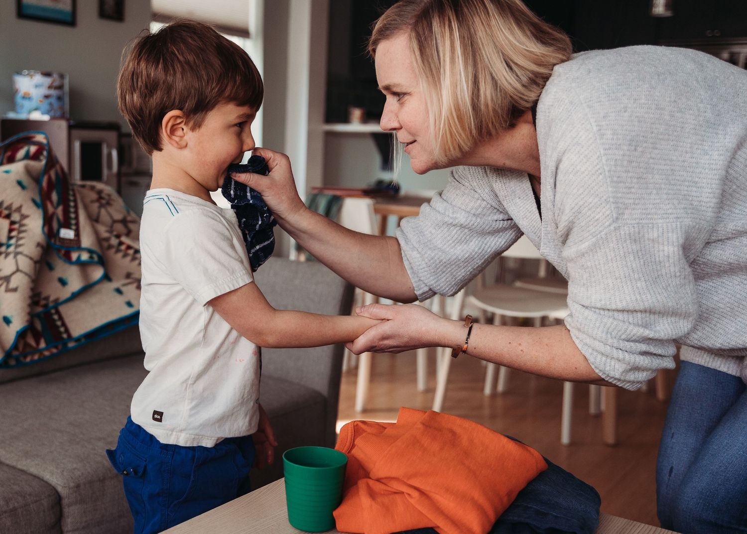 Parent and child interact playfully in living room setting with toys visible.