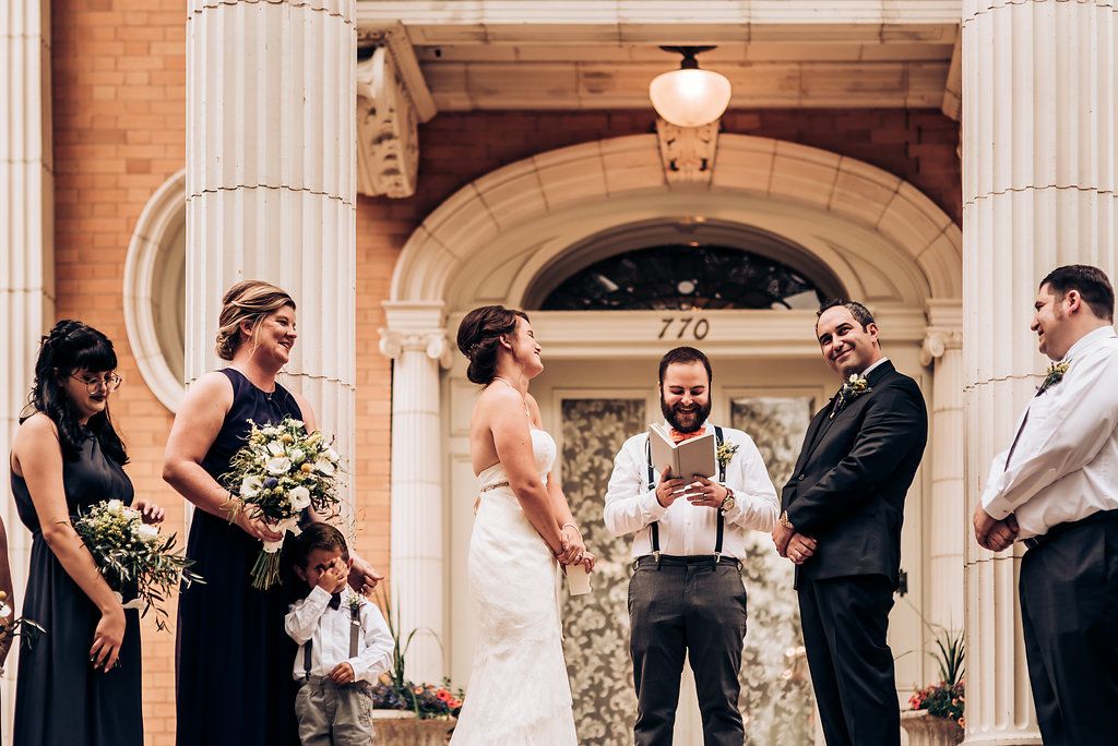 Wedding party stands before grand columns during outdoor ceremony.