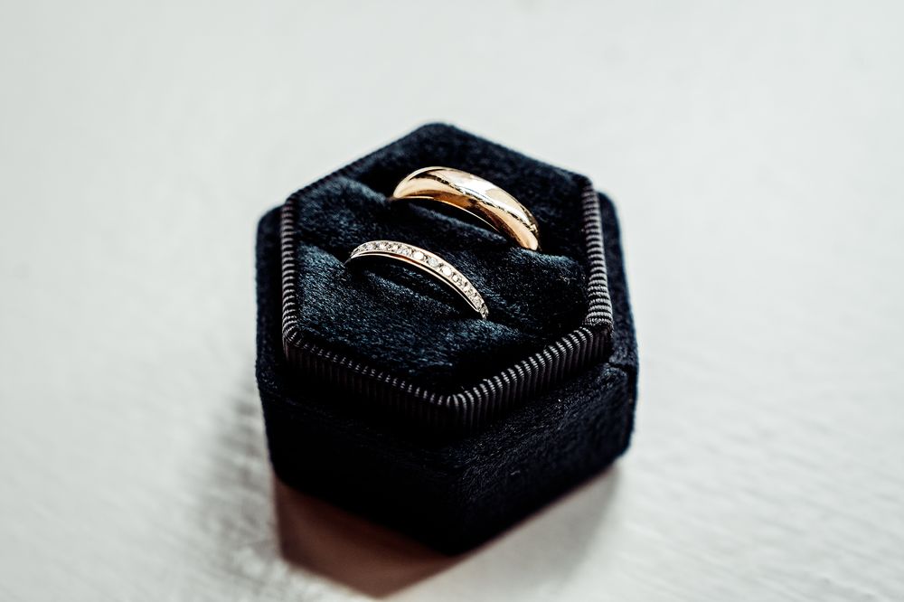 Two wedding rings nestled in a navy blue hexagonal velvet ring box.